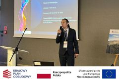 Mężczyzna przemawia do uczestników, w tle prezentacja. Po zdjęciem belka z logotypami KPO, flaga Polski oraz flaga Unii Europejskiej i napisem "Sfinansowano przez Unie Europejską".