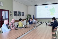 Sala konferencyjna, na środku stół, przy którym siedzą uczestnicy wizyty studyjnej, po lewej 5 osób, w tym jedna kobieta, po prawej 3 mężczyzn. W tle ekran z prezentacją.