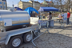 Stoiska promocyjne i samochód z wodą pitną podczas wydarzenia na Placu Zwycięstwa.